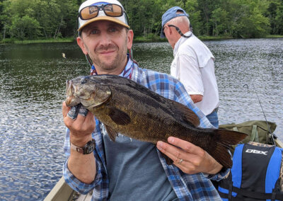 A visiting fisherman showing off his catch while fishing on Sebago Lake