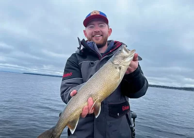 An excited fisherman showing off his catch during a cloudy day on Sebago Lake