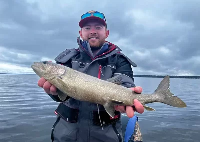 An angler showing off his catch during a cloudy day on Sebago Lake