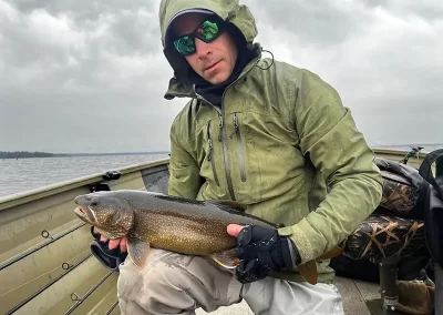 A stoic fisherman showing off his catch during a cloudy day on Sebago Lake