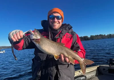 A happy fisherman showing off his catch during a sunny day on Sebago Lake