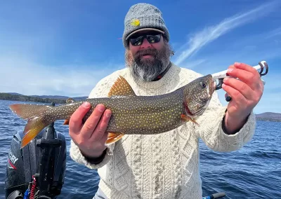 A happy fisherman showing off a fish after a sunny day on Sebago Lake