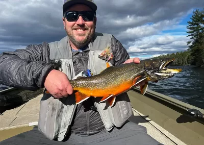 A smiling fisherman showing off his catch on a sunny day on Sebago Lake
