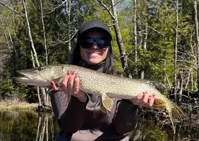 A happy fisherwoman showing off her catch after a sunny day on Sebago Lake