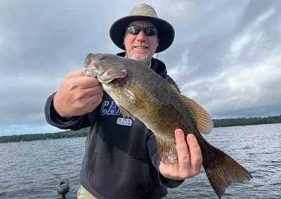 An avid fisherman showing off his catch on Sebago Lake