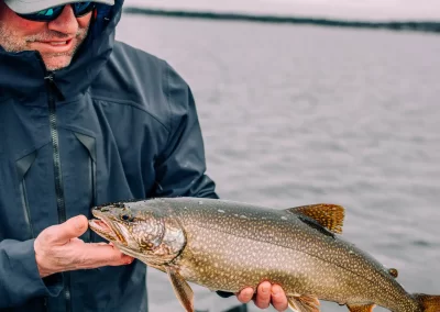 A happy fisherman showing off his catch from a fishing trip on Sebago Lake