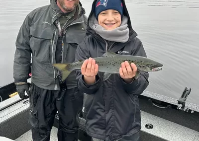 Guide Jon Peterson with a young angler showing off his catch on a Sebago Lake Fishing trip