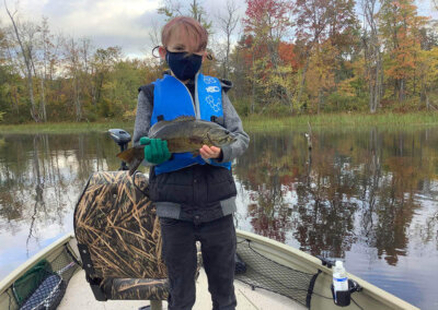 A young fisherman showing off his catch on a Sebago Lake fishing trip