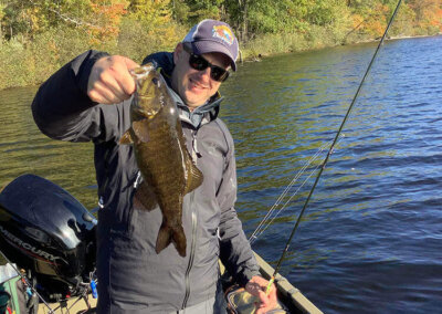 A visiting fisherman showing off his catch on a Sebago Lake Fishing trip